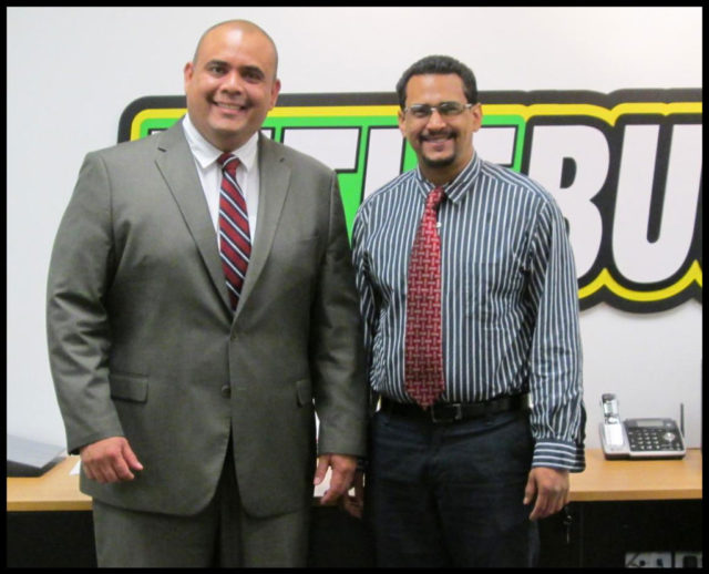 two men standing in front of a TitleBucks sign